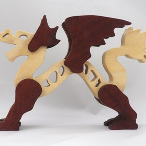 Handmade wooden dragon figurine. crafted from contrasting hardwoods with a light natural wood body and head paired with rich dark reddish-brown wings, legs, and horns.