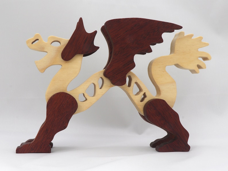Handmade wooden dragon figurine. crafted from contrasting hardwoods with a light natural wood body and head paired with rich dark reddish-brown wings, legs, and horns.
