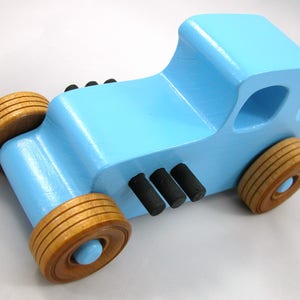 Handmade wooden toy car modeled after a '27 T-Coupe, finished with baby blue and black acrylic paint with nonmarring amber shellac wheels from my hot rod collection.