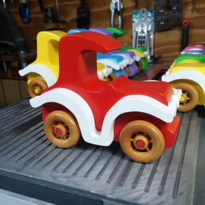 Handmade wooden toy car, vintage style red Model T Coupe by Odin's Toy Factory. Two-tone red and white acrylic paint with spoked wooden wheels finished in amber shellac. Approximate dimensions: 5 inches long, 4 inches high, 2.5 inches wide. Part of Bad Bob’s Custom Motors Collection. Crafted from natural wood using traditional woodworking tools. Handmade in Tallahassee, Florida, USA.