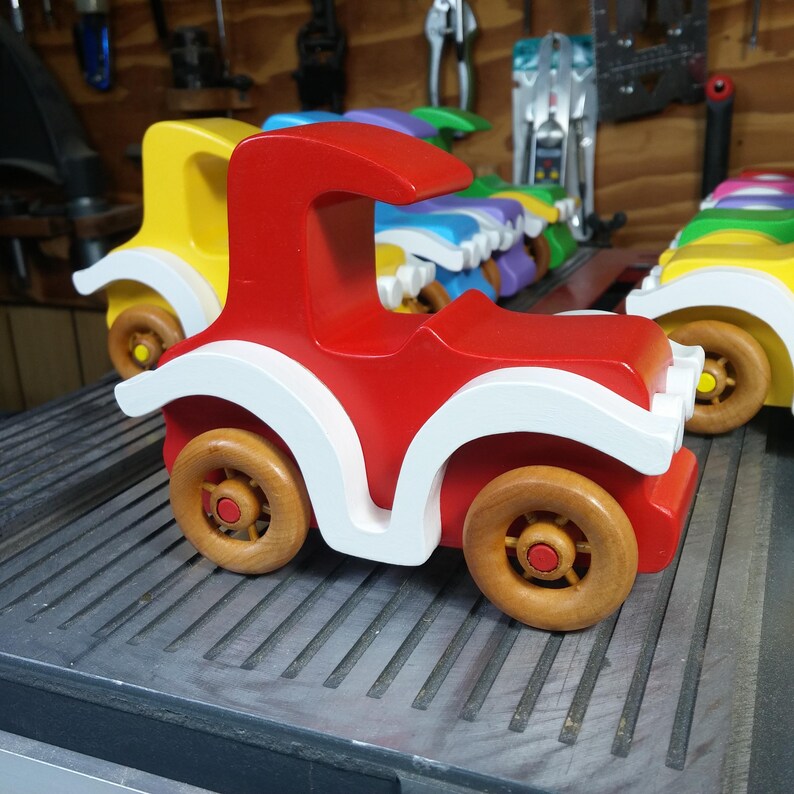 Handmade wooden toy car, vintage style red Model T Coupe by Odin's Toy Factory. Two-tone red and white acrylic paint with spoked wooden wheels finished in amber shellac. Approximate dimensions: 5 inches long, 4 inches high, 2.5 inches wide. Part of Bad Bob’s Custom Motors Collection. Crafted from natural wood using traditional woodworking tools. Handmade in Tallahassee, Florida, USA.