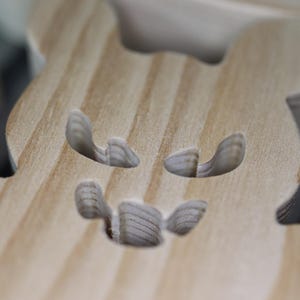 Close-up of a handmade wooden Halloween bat showing the scroll-sawn eyes and mouth, natural wood grain and smooth sanded surface.