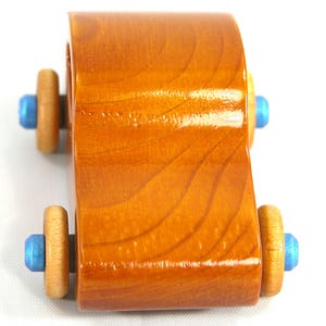 A handmade wooden toy car modeled after the iconic 1957 bug, finished with amber shellac and metallic sapphire blue trim. It's part of my Play Pal Collection.