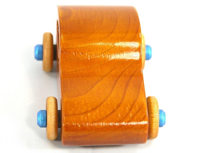 A handmade wooden toy car modeled after the iconic 1957 bug, finished with amber shellac and metallic sapphire blue trim. It's part of my Play Pal Collection.
