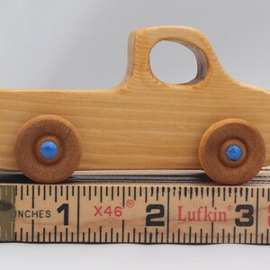 Wooden toy pickup truck from the Play Pal Collection at Odin's Toy Factory. Made from natural wood, finished with amber shellac, and accented with metallic sapphire blue acrylic paint on the wheel hubs. Made In The USA. Approximate dimensions: length 3-1/2 inches, height 1-3/8 inches, width 1-1/2 inches, wheels 3/4 inch diameter. Handmade in Tallahassee, Florida. Natural wood grain and color variations.