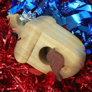 Handmade wooden miniature birdhouse ornament cut from wood with rounded edges, natural wood grain and color variations, finished with non-toxic shellac or food-safe oils and beeswax, lightweight and ready to hang. Made in Tallahassee, Florida, USA, by Odin's Toy Factory.