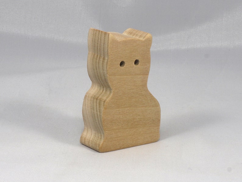 A handmade freestanding wooden toy cat cutout 1/2-3/4 inches thick is made from various kinds of wood sanded smooth and ready to paint. It is excellent for kids' crafts, pretend, or stacking toys. Other sizes are available with a custom order.