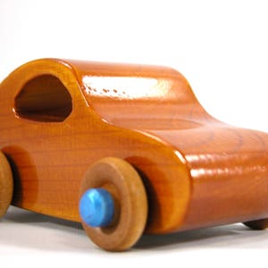 A handmade wooden toy car modeled after the iconic 1957 bug, finished with amber shellac and metallic sapphire blue trim. It's part of my Play Pal Collection.