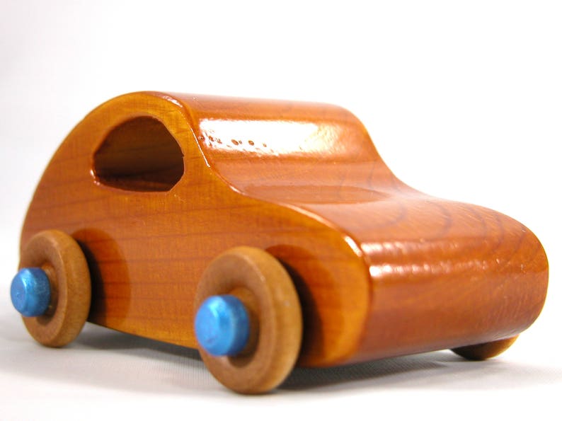 A handmade wooden toy car modeled after the iconic 1957 bug, finished with amber shellac and metallic sapphire blue trim. It's part of my Play Pal Collection.