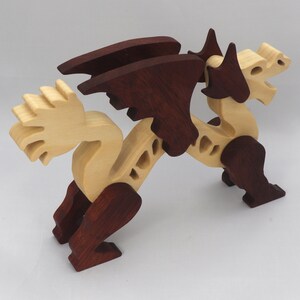 Handmade wooden dragon figurine. crafted from contrasting hardwoods with a light natural wood body and head paired with rich dark reddish-brown wings, legs, and horns.