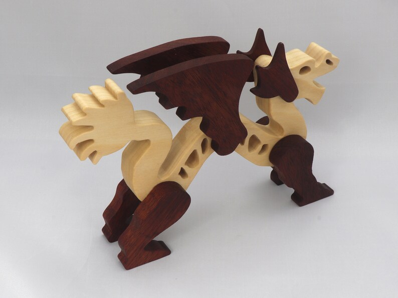 Handmade wooden dragon figurine. crafted from contrasting hardwoods with a light natural wood body and head paired with rich dark reddish-brown wings, legs, and horns.