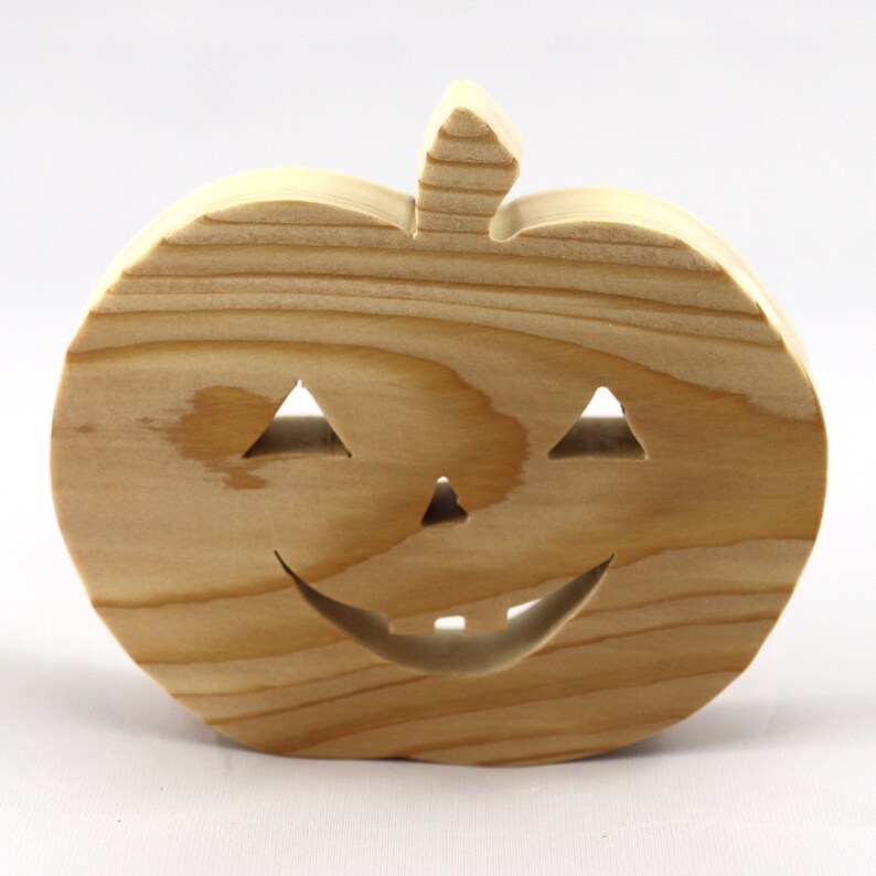 Handmade unpainted wooden Jack-o-Lantern cutout with carved triangular eyes, nose, smiling mouth, and stem, shown freestanding on a white background. Ready to paint for Halloween decoration.