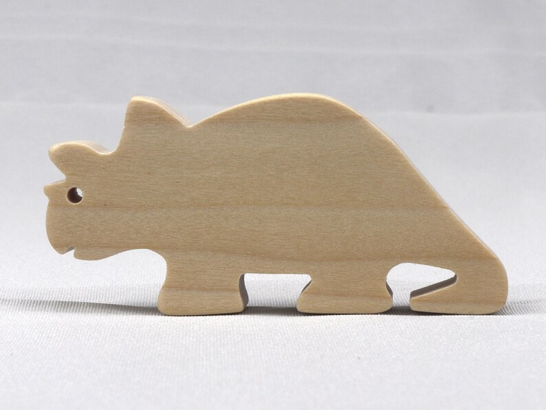 This is an unfinished wooden Wooden Toy Dinosaur Triceratops cutout from solid wood using traditional woodworking techniques. Sanded smooth and ready to paint, stain, or customize. Freestanding design for small hands, toddlers, young children, crafters, collectors, and display. I take custom orders for any animal, quantity, and mix — including large ornament orders. Mix and match, request a different size, or send a drawing or pattern. Handmade by Odin's Toy Factory in Tallahassee, Florida, USA.