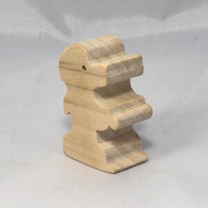 May include: A wooden toy shaped like a person, standing upright with arms outstretched. The toy is made of light brown wood and has a simple, minimalist design.