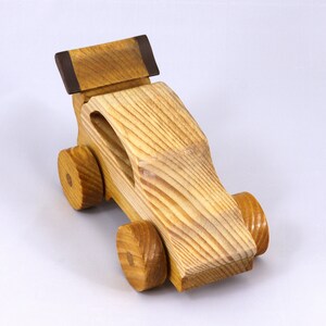 Handmade wooden toy car finished with nontoxic clear amber shellac and contrasting wood trim. Part of the Speedy Wheels Collection. Handcrafted in Tallahassee, Florida, USA. Length 5-1/2 inches, width 2-1/2 inches, height 2-1/2 inches. Made at Odin's Toy Factory.