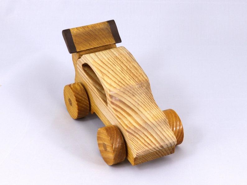 Handmade wooden toy car finished with nontoxic clear amber shellac and contrasting wood trim. Part of the Speedy Wheels Collection. Handcrafted in Tallahassee, Florida, USA. Length 5-1/2 inches, width 2-1/2 inches, height 2-1/2 inches. Made at Odin's Toy Factory.