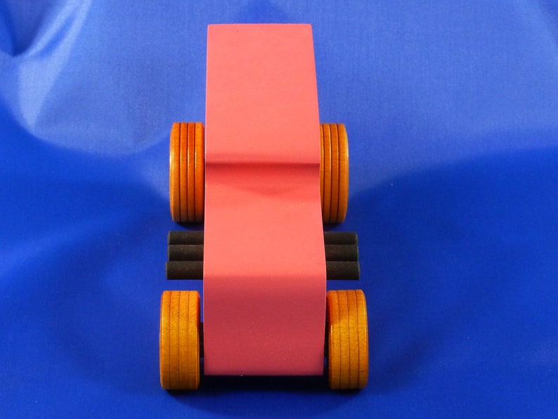 Handcrafted pink wooden hot rod '32 sedan toy car. Features black and metallic sapphire blue accents, and non-marking amber shellac wheels. Made to order for unique play or display.