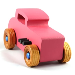 This is a handmade wooden Hot Rod '32 Deuce Coupe toy car. It is hand-painted hot pink with black and metallic sapphire blue trim. The hardwood wheels are finished with nonmarring amber shellac.