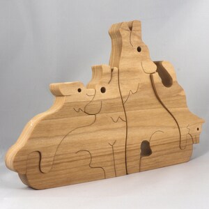 Wooden Wolf Family Stacking Puzzle is handmade from hardwood and finished with mineral oil, beeswax, and carnauba wax. Freestanding interlocking wolf family puzzle pieces shown assembled. Approximate size 10.5 inches long by 6.7 inches high by 3/4 inch thick. Handmade in Tallahassee, Florida, USA.