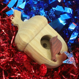Handmade wooden miniature birdhouse ornament cut from wood with rounded edges, natural wood grain and color variations, finished with non-toxic shellac or food-safe oils and beeswax, lightweight and ready to hang. Made in Tallahassee, Florida, USA, by Odin's Toy Factory.