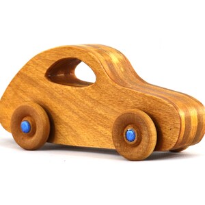 May include: A wooden toy car with blue wheels. The car is made of light brown wood with a striped pattern.