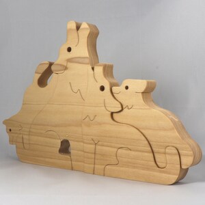 Wooden Wolf Family Stacking Puzzle is handmade from hardwood and finished with mineral oil, beeswax, and carnauba wax. Freestanding interlocking wolf family puzzle pieces shown assembled. Approximate size 10.5 inches long by 6.7 inches high by 3/4 inch thick. Handmade in Tallahassee, Florida, USA.