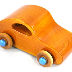 A handmade wooden toy car modeled after the iconic 1957 bug, finished with amber shellac and metallic sapphire blue trim. It's part of my Play Pal Collection.
