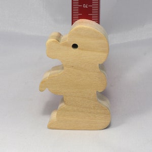 May include: A wooden toy shaped like a standing bear. The bear is light brown and has a simple design.