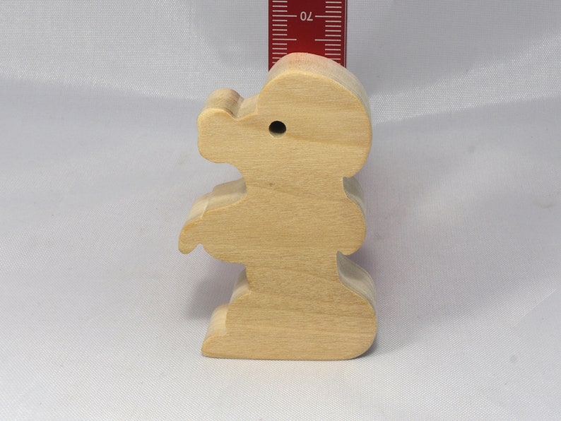 May include: A wooden toy shaped like a standing bear. The bear is light brown and has a simple design.