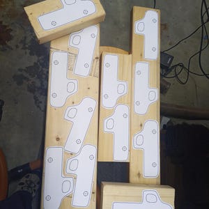 Overhead view of paper toy pickup truck patterns arranged on pine boards, with cab windows and axle holes marked for cutting.