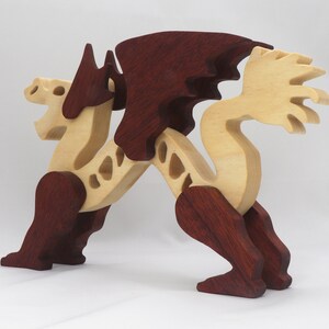 Handmade wooden dragon figurine. crafted from contrasting hardwoods with a light natural wood body and head paired with rich dark reddish-brown wings, legs, and horns.