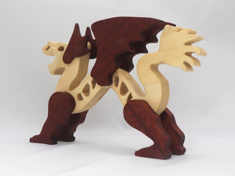 Handmade wooden dragon figurine. crafted from contrasting hardwoods with a light natural wood body and head paired with rich dark reddish-brown wings, legs, and horns.