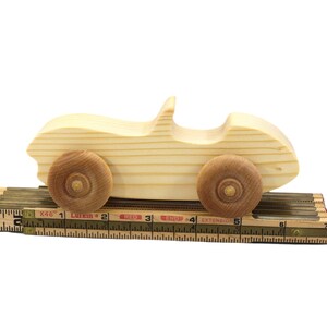 A small, handcrafted wooden toy convertible sports car, finished with a custom blend of oils and waxes, is the perfect gift for young children.