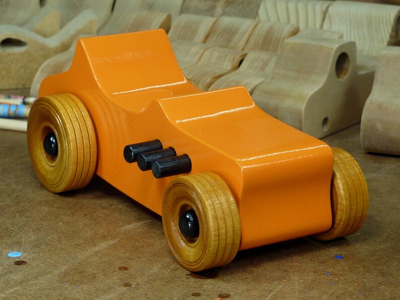 Handmade wooden toy car modeled after a 1927 T-Bucket hot rod. Finished with orange and black acrylic paint and amber shellac.