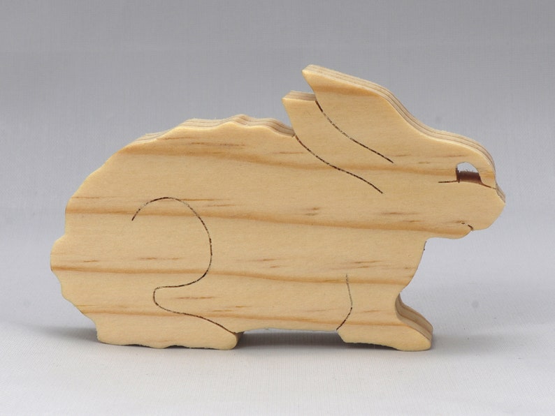 This is an unfinished wooden Rabbit cutout from solid wood using traditional woodworking techniques. Sanded smooth and ready to paint, stain, or customize. Freestanding design for small hands, toddlers, young children, crafters, collectors, and display. I take custom orders for any animal, quantity, and mix — including large ornament orders. Mix and match, request a different size, or send a drawing or pattern. Handmade by Odin's Toy Factory in Tallahassee, Florida, USA.