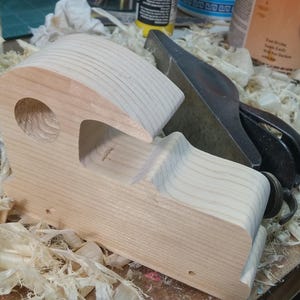 Odin' Toy Factory Toymakers Shop Photo - Handmade wooden toy car body under construction. Various tools are used to smooth and round the corners. There is lots of hand sanding.