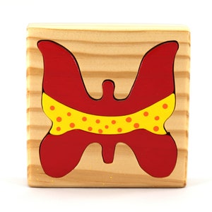 A wooden three-piece butterfly tray puzzle, handmade and finished. The butterfly is painted bright red and yellow with orange spots. The wooden tray is finished with clear shellac. It is one of four puzzles in my Puzzle Pals Collection.
