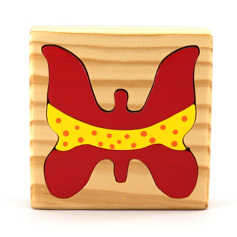 A wooden three-piece butterfly tray puzzle, handmade and finished. The butterfly is painted bright red and yellow with orange spots. The wooden tray is finished with clear shellac. It is one of four puzzles in my Puzzle Pals Collection.