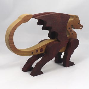 AHandmade wooden dragon figurine made from contrasting hardwoods with a light natural wood body and head paired with rich dark reddish-brown wings, legs, and horns.
