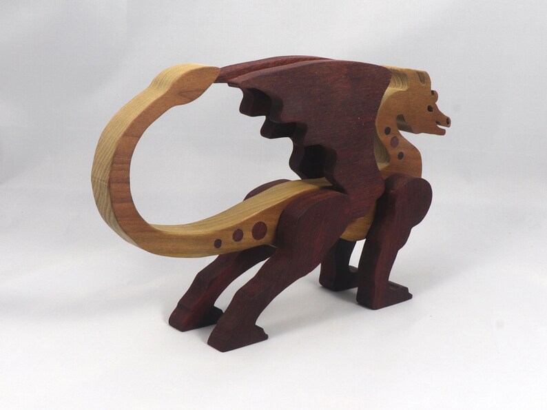 AHandmade wooden dragon figurine made from contrasting hardwoods with a light natural wood body and head paired with rich dark reddish-brown wings, legs, and horns.