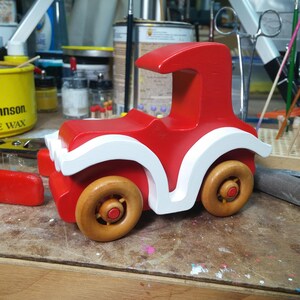 Handmade wooden toy car, vintage style red Model T Coupe by Odin's Toy Factory. Two-tone red and white acrylic paint with spoked wooden wheels finished in amber shellac. Approximate dimensions: 5 inches long, 4 inches high, 2.5 inches wide. Part of Bad Bob’s Custom Motors Collection. Crafted from natural wood using traditional woodworking tools. Handmade in Tallahassee, Florida, USA.