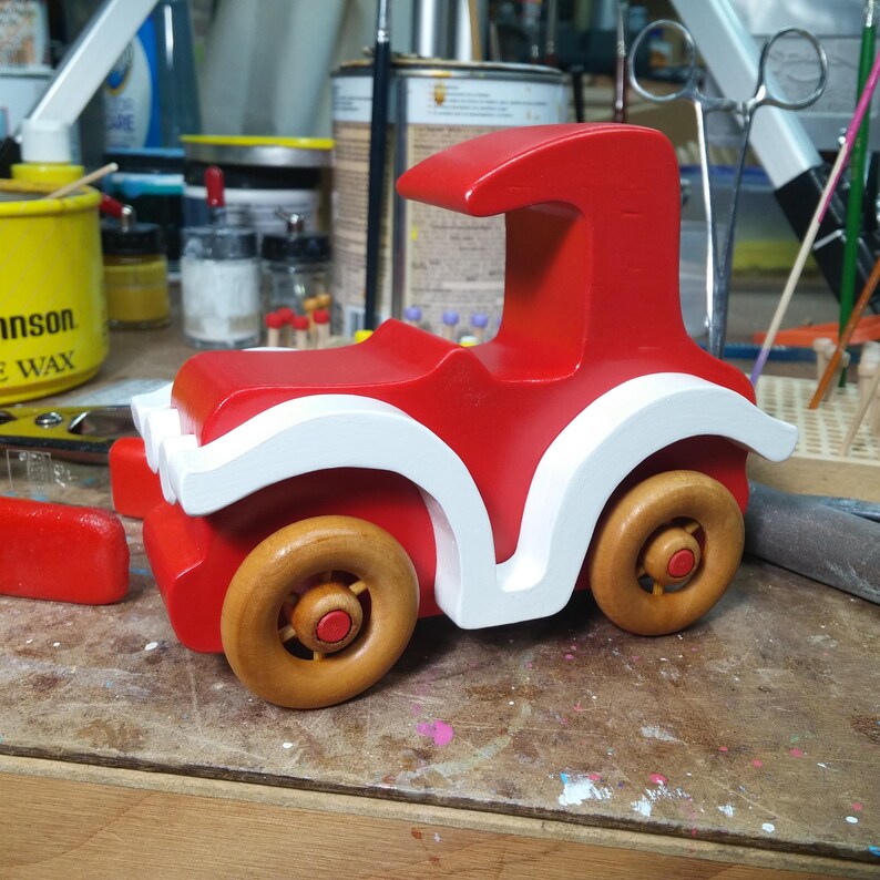 Handmade wooden toy car, vintage style red Model T Coupe by Odin's Toy Factory. Two-tone red and white acrylic paint with spoked wooden wheels finished in amber shellac. Approximate dimensions: 5 inches long, 4 inches high, 2.5 inches wide. Part of Bad Bob’s Custom Motors Collection. Crafted from natural wood using traditional woodworking tools. Handmade in Tallahassee, Florida, USA.