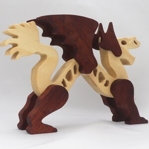 Handmade wooden dragon figurine. crafted from contrasting hardwoods with a light natural wood body and head paired with rich dark reddish-brown wings, legs, and horns.