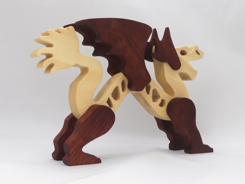 Handmade wooden dragon figurine. crafted from contrasting hardwoods with a light natural wood body and head paired with rich dark reddish-brown wings, legs, and horns.