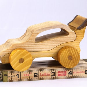 Handmade wooden toy car finished with nontoxic clear amber shellac and contrasting wood trim. Part of the Speedy Wheels Collection. Handcrafted in Tallahassee, Florida, USA. Length 5-1/2 inches, width 2-1/2 inches, height 2-1/2 inches. Made at Odin's Toy Factory.