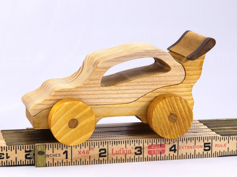 Handmade wooden toy car finished with nontoxic clear amber shellac and contrasting wood trim. Part of the Speedy Wheels Collection. Handcrafted in Tallahassee, Florida, USA. Length 5-1/2 inches, width 2-1/2 inches, height 2-1/2 inches. Made at Odin's Toy Factory.
