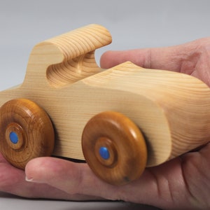 Handmade wooden toy car. The body is finished with clear shellac, and the wheels are finished with amber shellac. The hubs are painted with metallic sapphire blue trim.