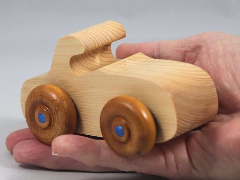 Handmade wooden toy car. The body is finished with clear shellac, and the wheels are finished with amber shellac. The hubs are painted with metallic sapphire blue trim.