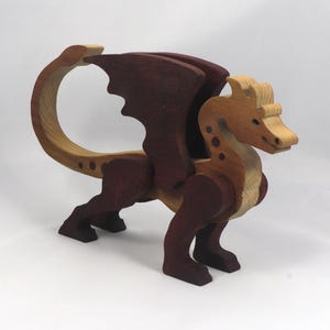 Handmade wooden dragon figurine made from contrasting hardwoods with a light natural wood body and head paired with rich dark reddish-brown wings, legs, and horns.