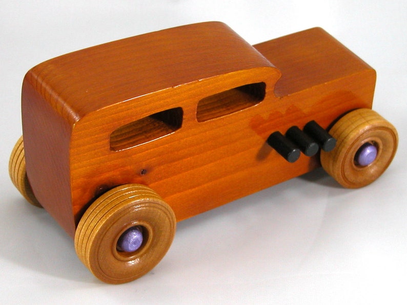 This is a handmade wooden toy car modeled after a Hot Rod 1932 Ford Sedan. It is made from wood, finished with multiple coats of amber shellac, and trimmed with black and metallic purple acrylic paint.